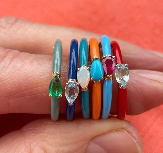 Thin banned ring with pear shaped gemstones and various enamels pictured colofully in a stack