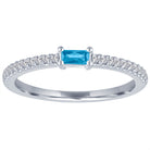 White gold skinny band with a blue topaz baguette in the center and round diamonds on the shank.