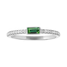 White gold skinny band with a bezeled emerald baguette in the center and round diamonds on the shank.