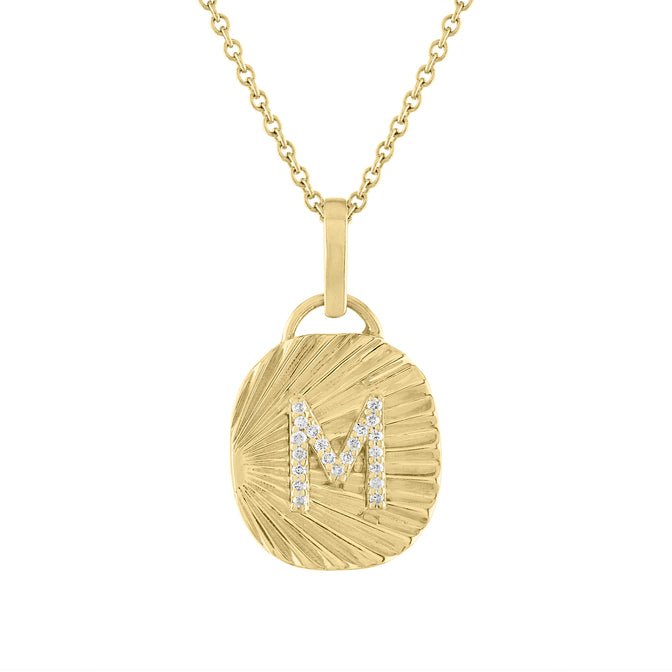 Yellow gold oval shaped necklace with fluting and a diamond initial in the center.