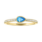 Yellow gold skinny band with a bezeled pear shape blue topaz in the center and round diamonds on the shank.