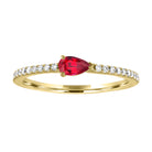 Yellow gold skinny band with pear shaped ruby in the center and round diamonds on the shank.