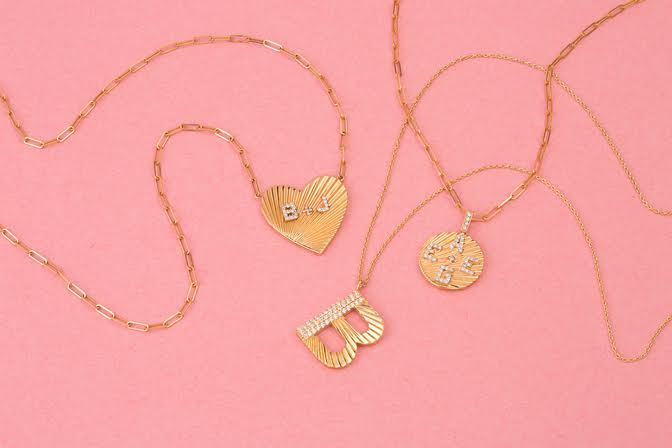 Round yellow gold disc necklace with fluting and diamond initials shown with other fluted necklaces with diamonds 