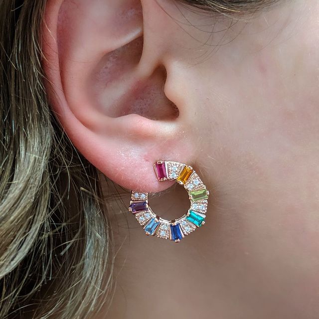 Rose gold huggy earrings with multi color baguettes and round diamonds shown on ear