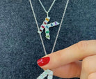 Mini white gold initial necklace with rainbow baguettes and round diamonds shown layered perfectly on the neck