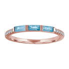 Rose gold skinny band with three aquamarine baguettes and round diamonds on the shank. 