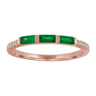 Rose gold skinny band with three emerald baguettes and round diamonds on the shank. 