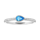 White gold skinny band with a bezeled pear shape blue topaz in the center and round diamonds on the shank. 