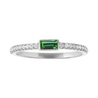 White gold skinny band with a bezeled emerald baguette in the center and round diamonds on the shank. 