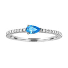 White gold skinny band with a pear shaped blue topaz in the center and round diamonds on the shank.