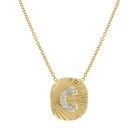 Yellow gold oval shaped necklace with fluting and a diamond initial in the center.